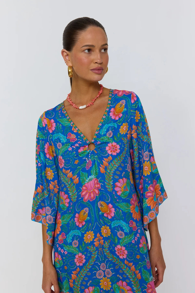Woman wearing a colorful floral dress against a white background