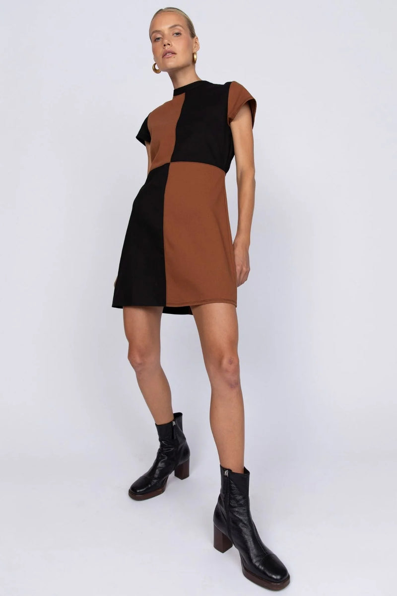 Woman wearing a black and brown dress with black boots on a white background