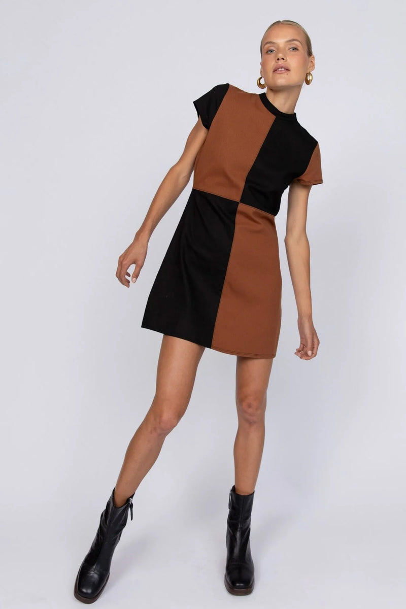 Woman wearing a brown and black dress with black boots on a white background