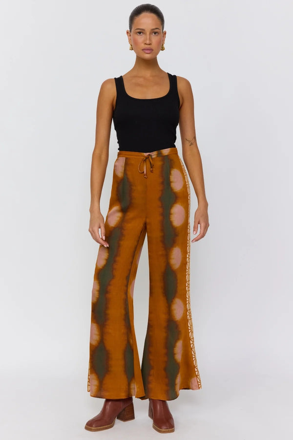 Woman wearing a black top and patterned brown pants on a white background