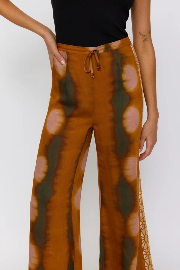 Brown tie-dye pants with a black top on a white background
