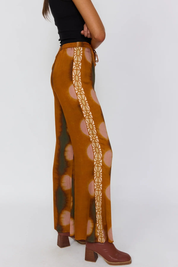 Brown patterned pants with a decorative side stripe on a white background