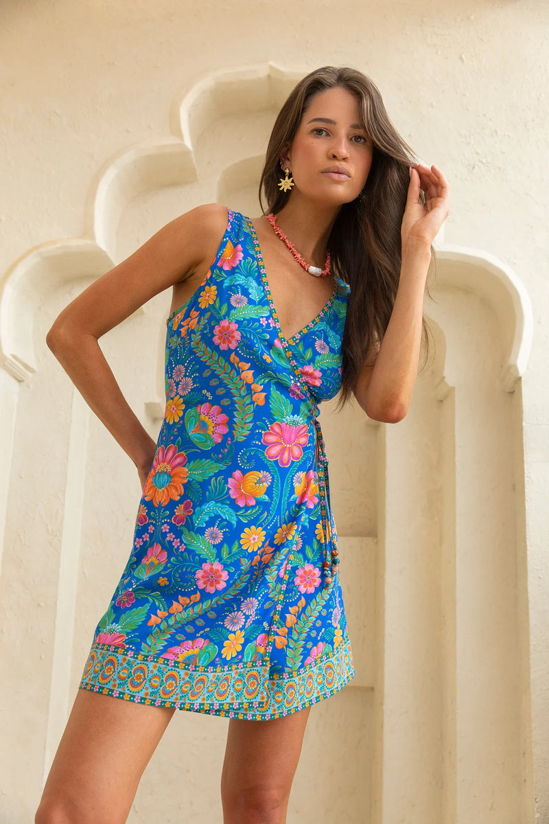 Woman wearing a colorful floral dress against a white architectural background