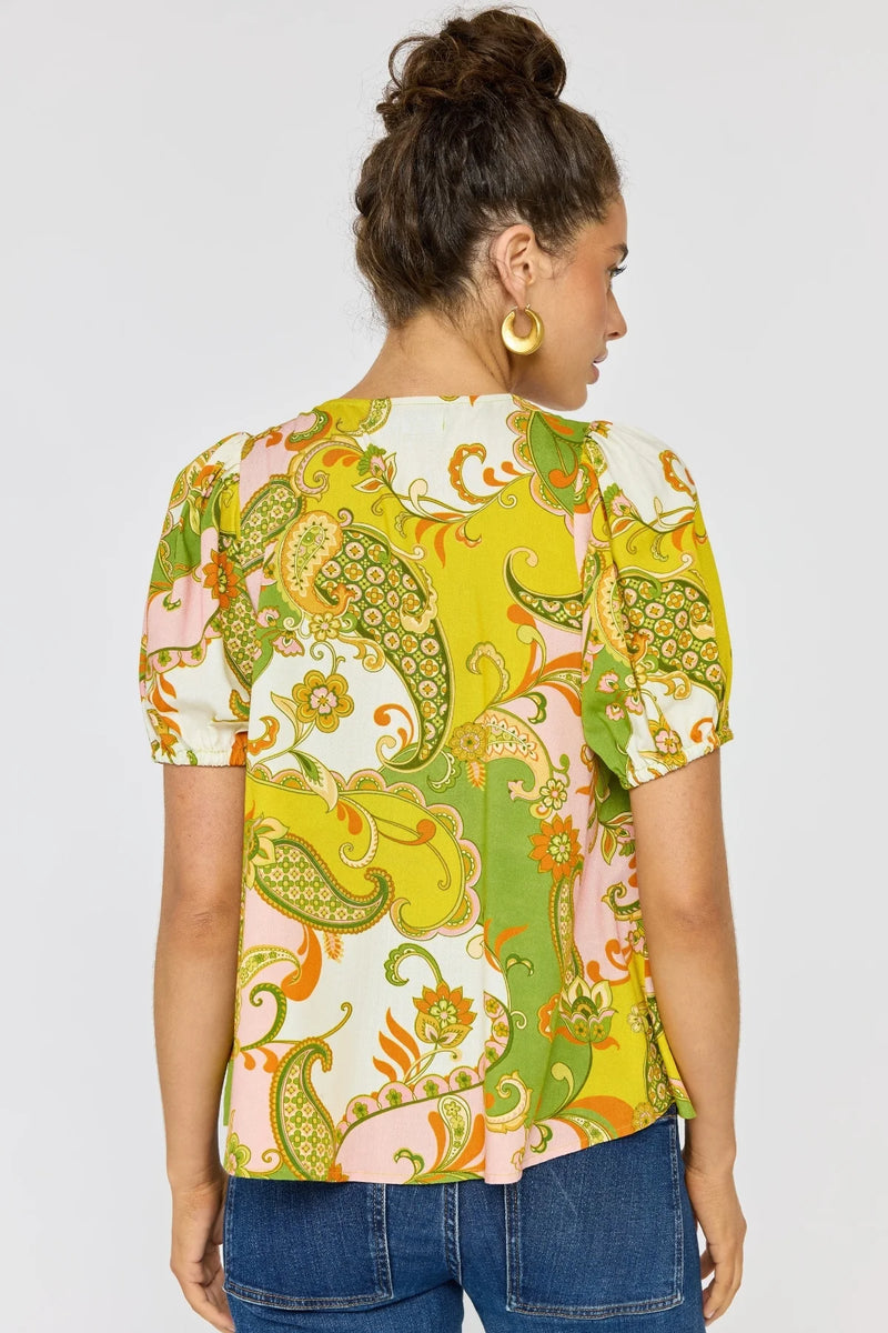 Woman wearing a colorful patterned top with a plain background