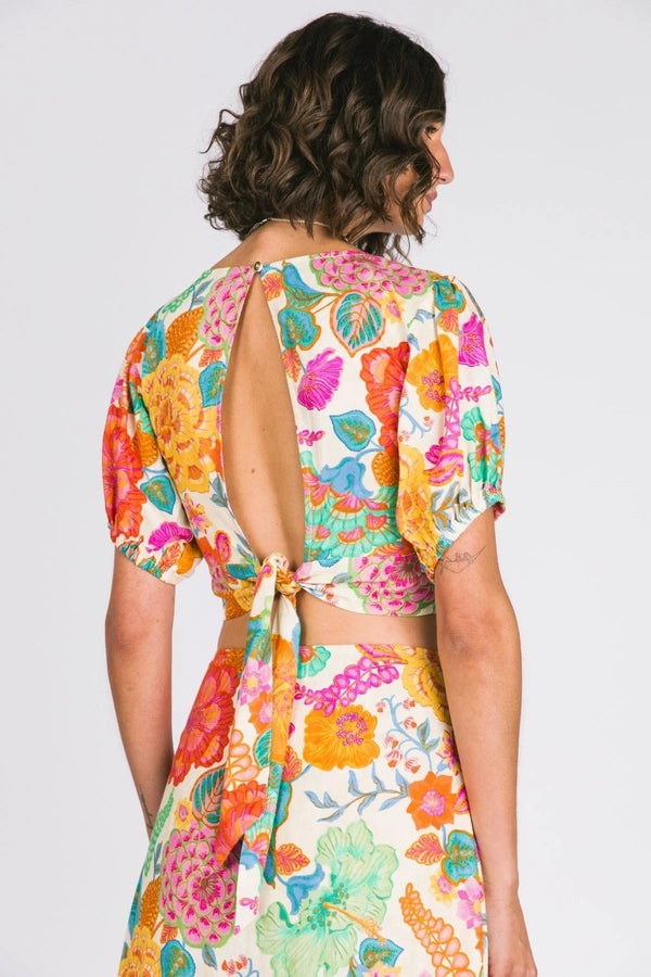 Woman wearing a colorful floral dress with an open back on a white background