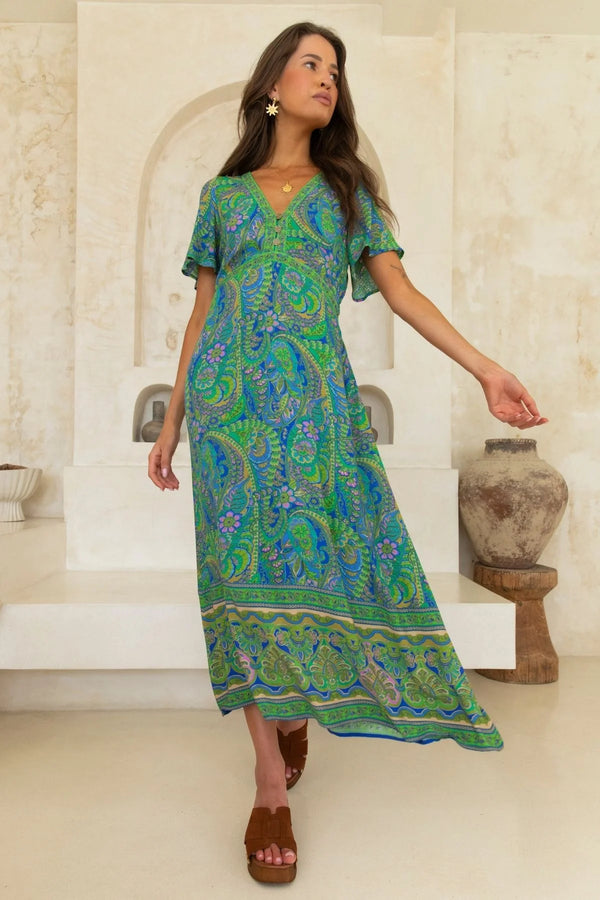 Woman wearing a green and blue patterned dress in an indoor setting.