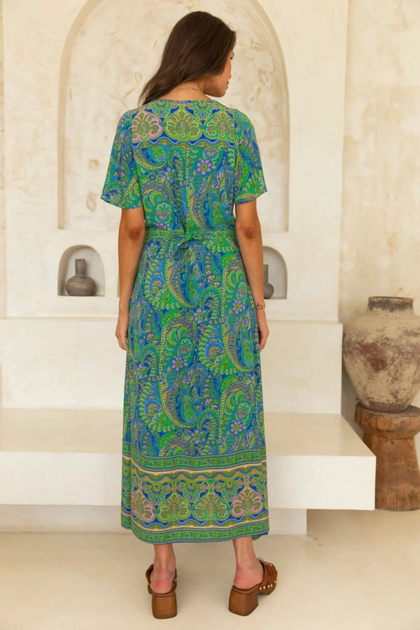 Woman wearing a green and blue patterned dress in an indoor setting.