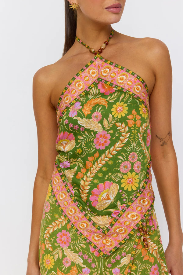 Woman wearing a green floral halter dress with a white background