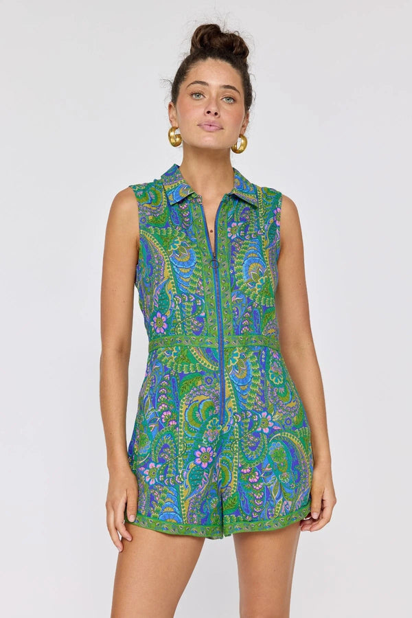 Woman wearing a sleeveless green and blue patterned dress against a white background