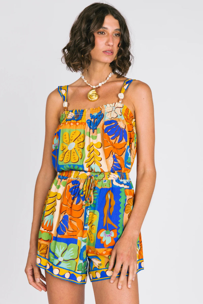 Woman wearing a colorful floral jumpsuit on a plain background