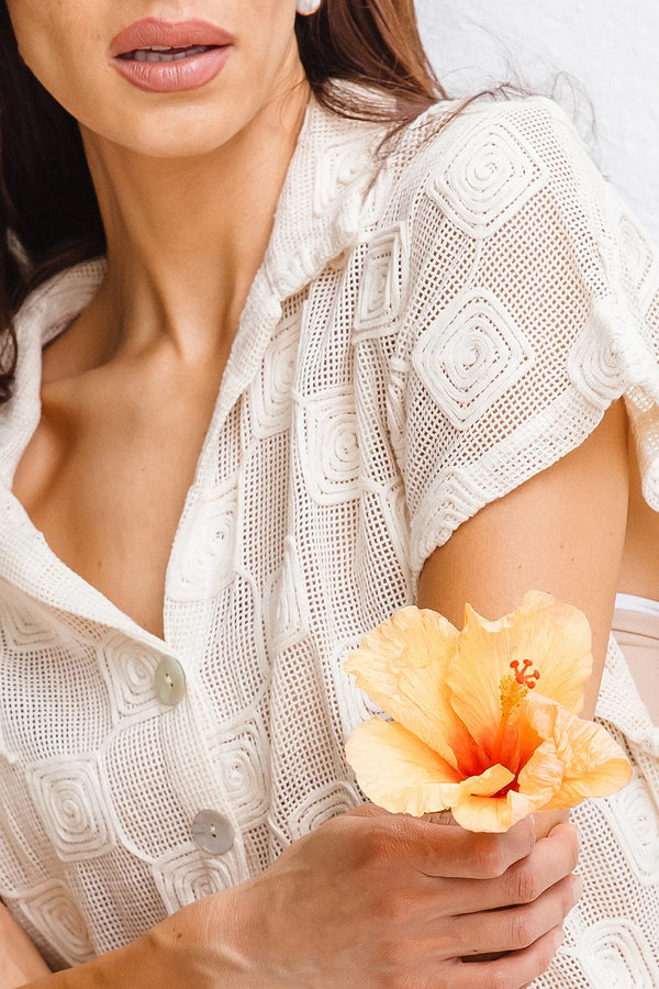 Woman holding a yellow flower against a neutral background