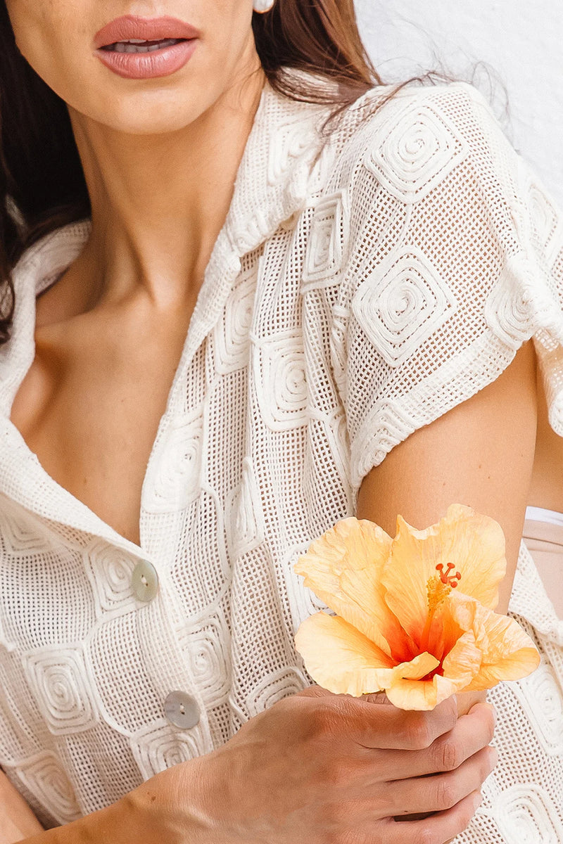 Woman holding a yellow flower against a neutral background