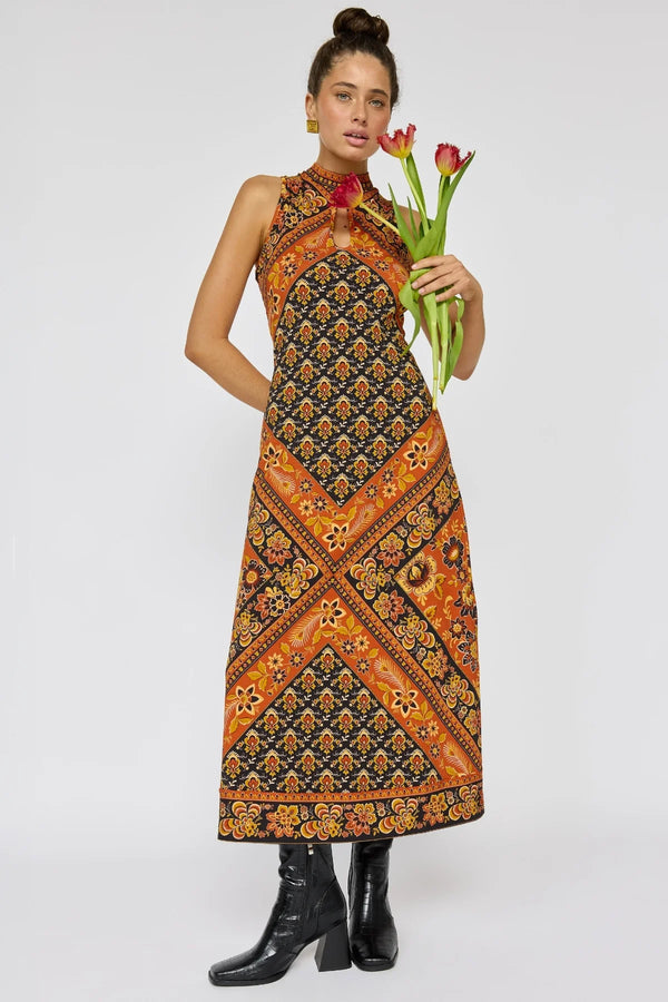 Woman wearing a patterned dress holding tulips against a white background