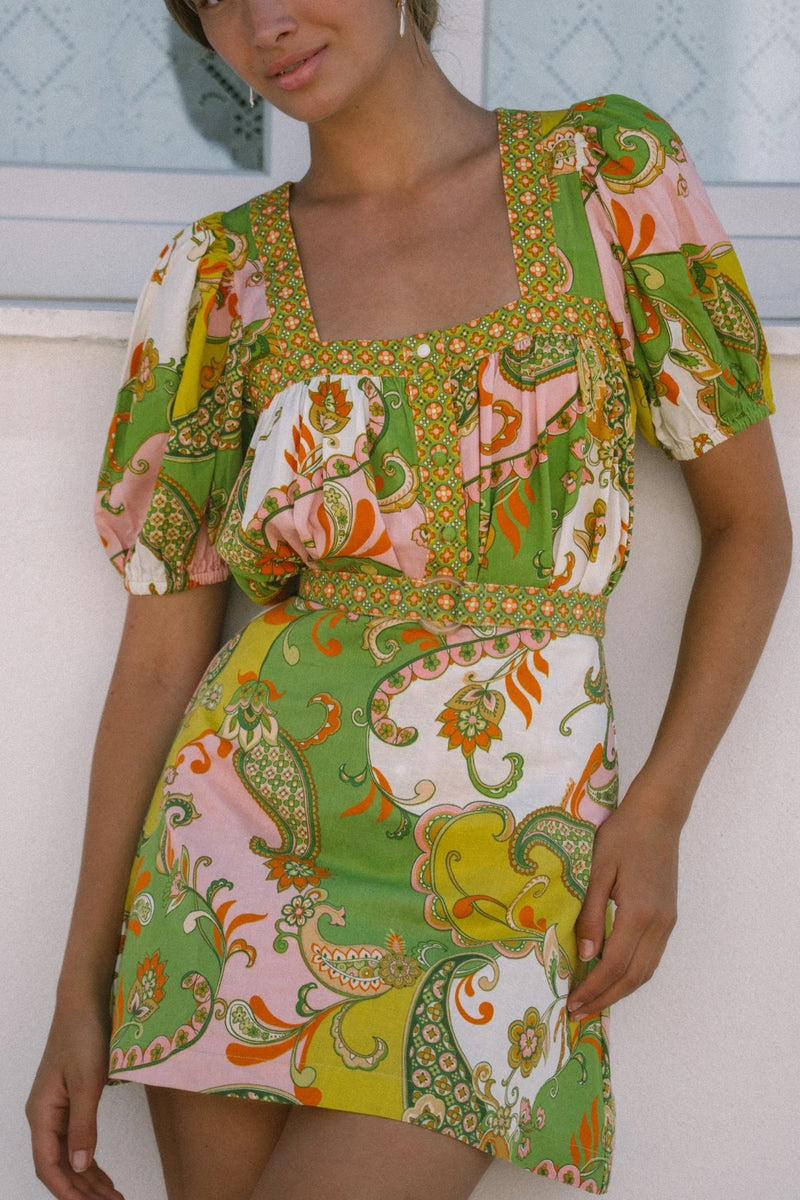 Woman wearing a colorful patterned dress with a white background