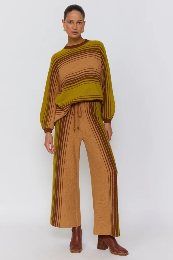 Woman wearing a mustard and brown outfit with a white background