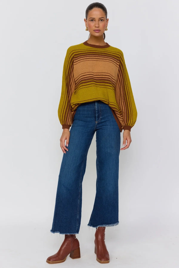 Woman wearing a striped sweater, blue jeans, and brown boots on a white background