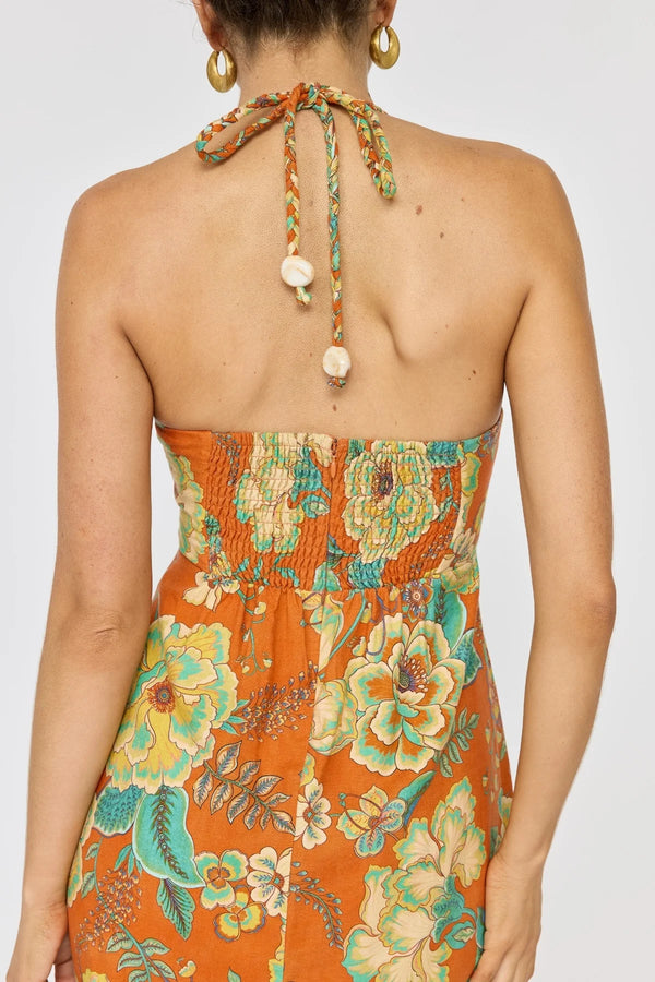 Woman wearing a floral dress with a colorful halter neck design on a white background