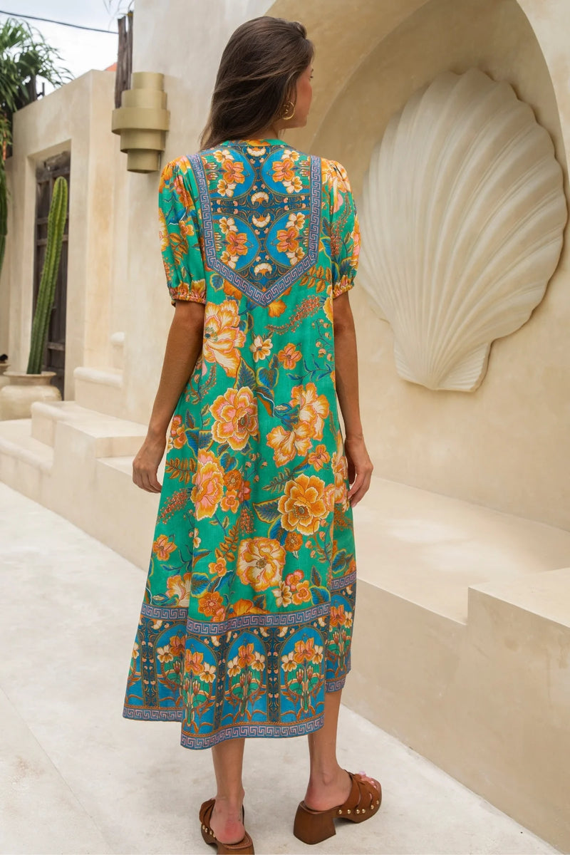 Woman wearing a floral dress with a decorative back design in an outdoor setting.