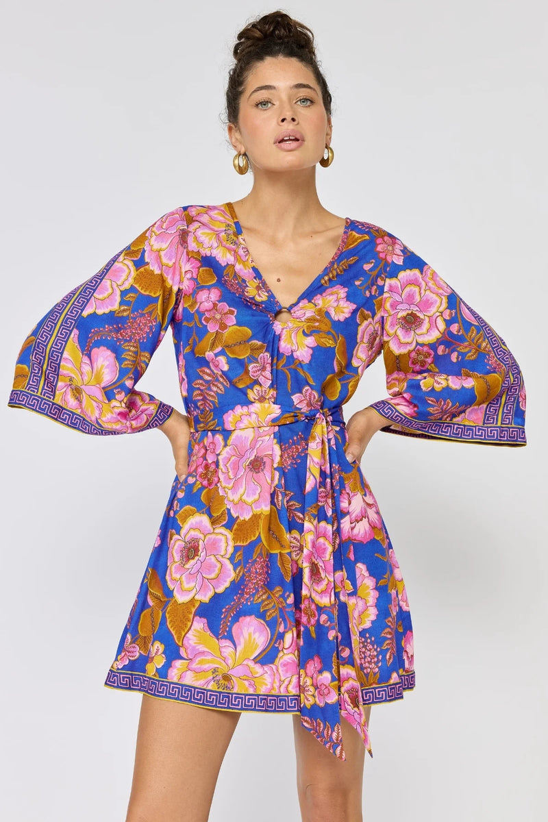 Woman wearing a colorful floral dress with bell sleeves on a white background