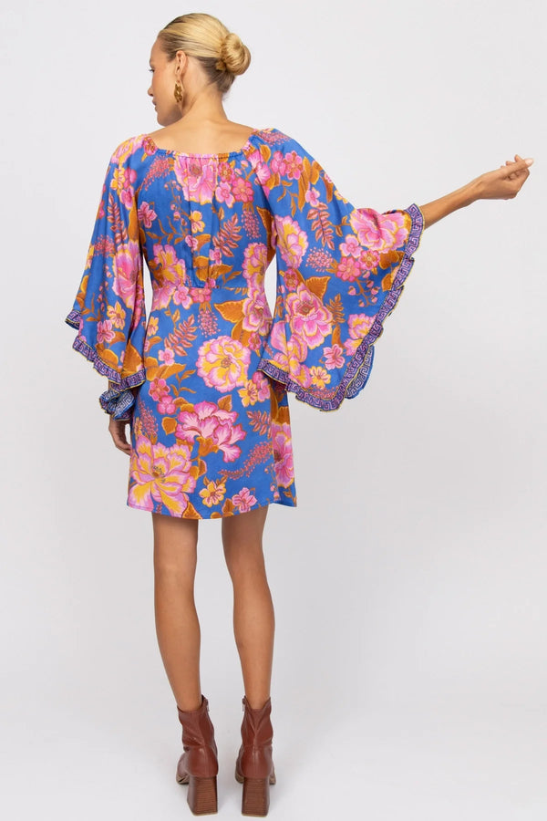 Woman wearing a colorful floral dress with bell sleeves on a white background