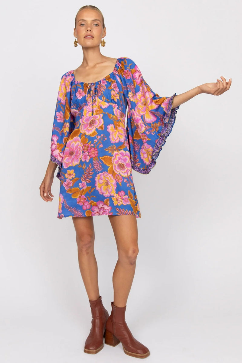 Woman wearing a colorful floral dress with bell sleeves on a white background