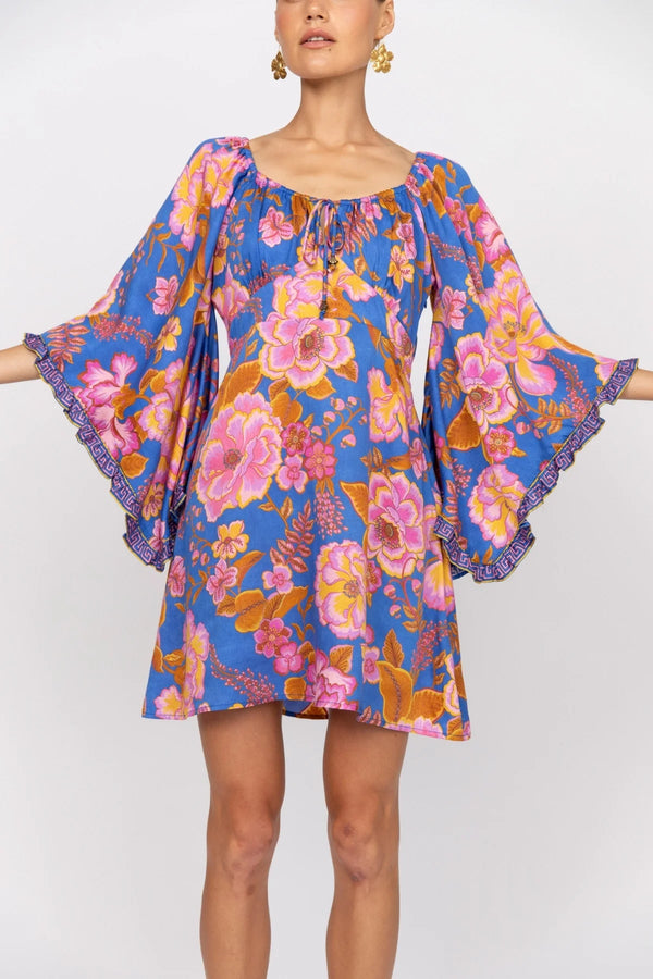 Woman wearing a colorful floral dress with bell sleeves on a white background