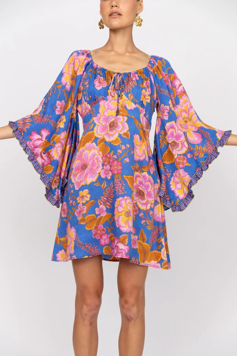 Woman wearing a colorful floral dress with bell sleeves on a white background