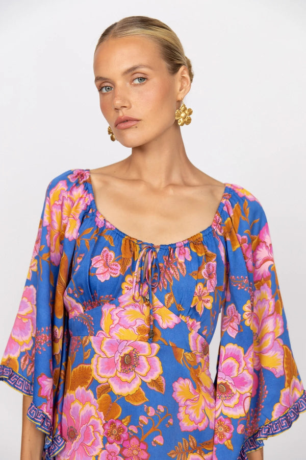 Woman wearing a colorful floral blouse against a white background