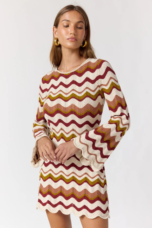 Woman wearing a colorful zigzag patterned dress on a white background
