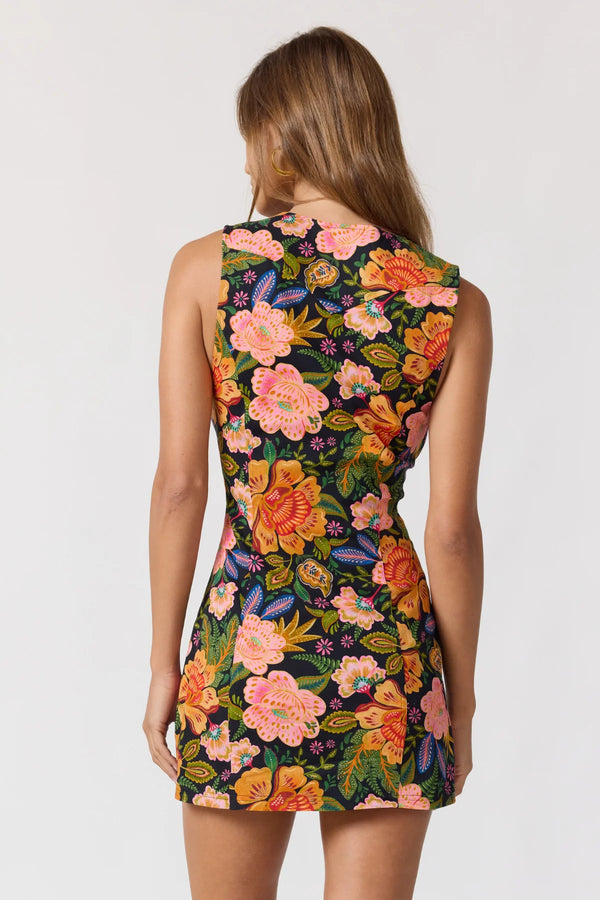 Woman wearing a sleeveless dress with a colorful floral pattern on a white background