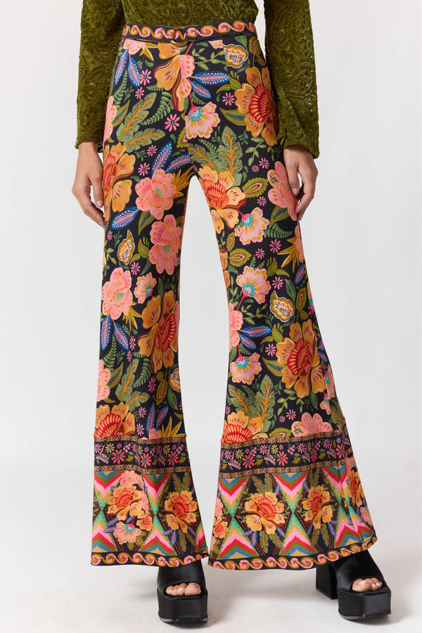 Flared pants with a colorful floral pattern worn by a person on a white background