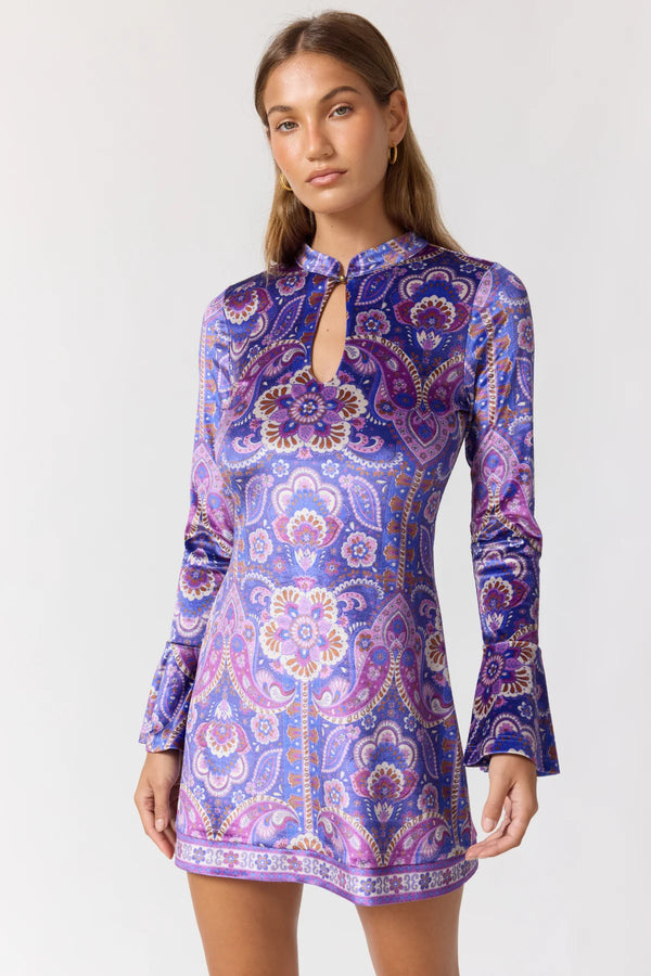 Woman wearing a purple paisley patterned dress on a white background