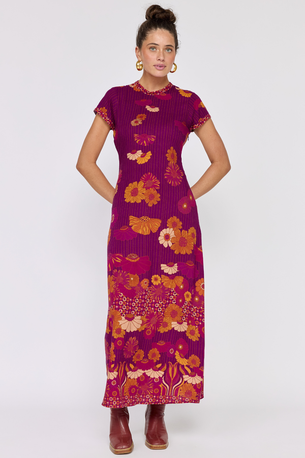 Woman wearing a vibrant purple dress with floral patterns on a white background