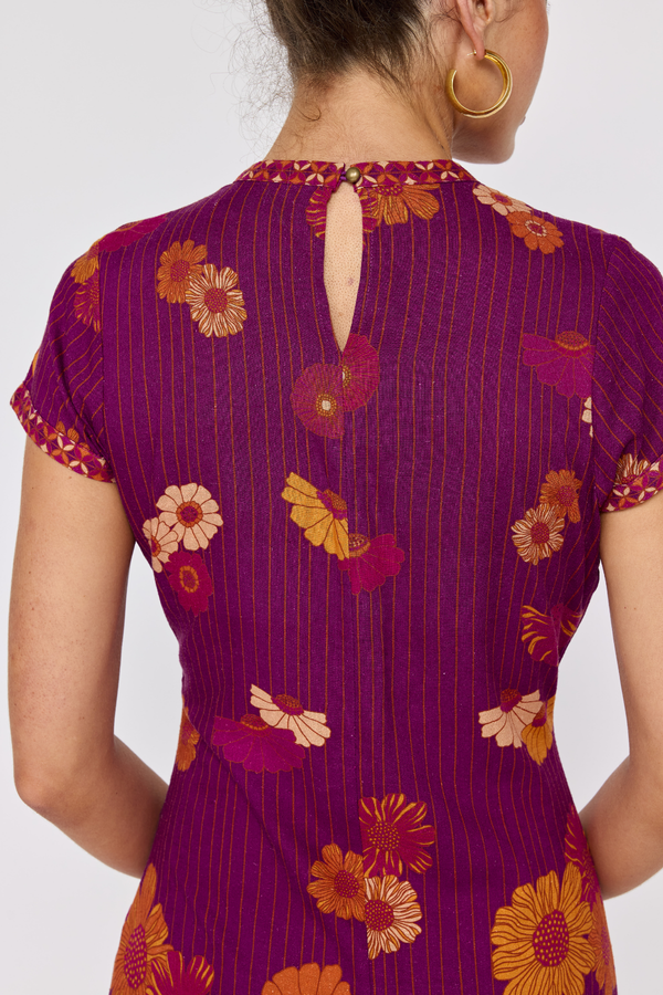 Purple dress with floral pattern worn by a person on a white background