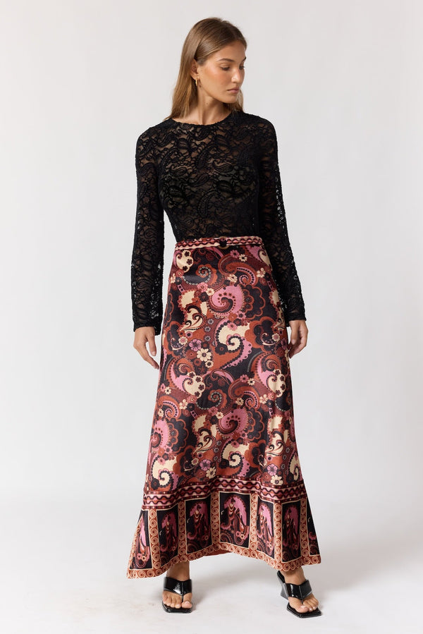 Woman wearing a black lace top and patterned skirt on a white background
